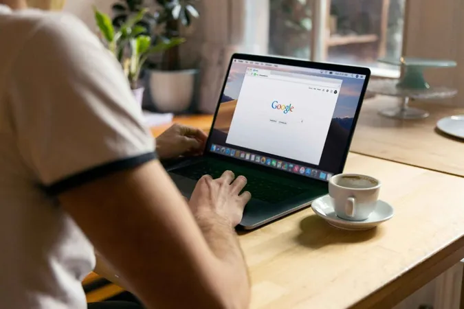 Un uomo che incolla qualcosa nella barra di ricerca di Google su un computer portatile.