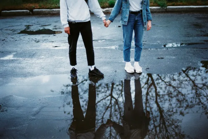 Two people standing on a wet road, holding hands