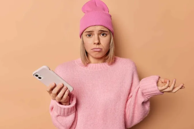 Upset girl looking at her phone, possibly reacting to being blocked on social media.